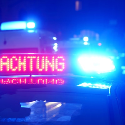 Das Bild zeigt einen Polizeiwagen in der Dunkelheit mit eingeschaltetem Blaulicht.
