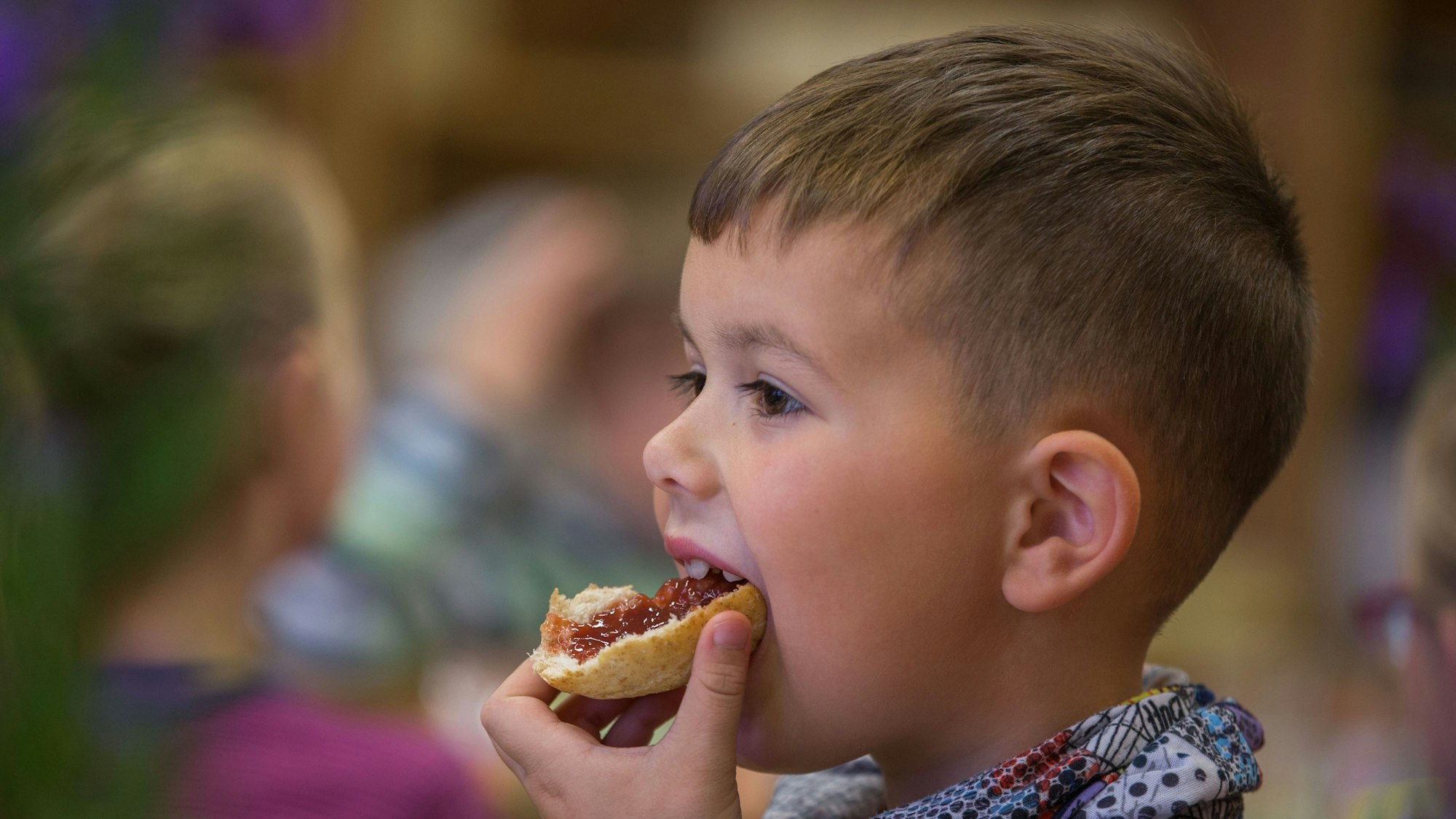 Ein Sechsjähriger beisst in ein Bio-Marmeladenbrötchen.