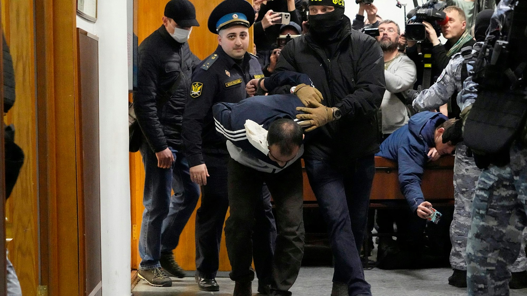 Ein Tatverdächtiger des Terroranschlags auf die Konzerthalle Crocus City Hall wird von Polizisten und FSB-Beamten im Basmanny-Bezirksgericht eskortiert.