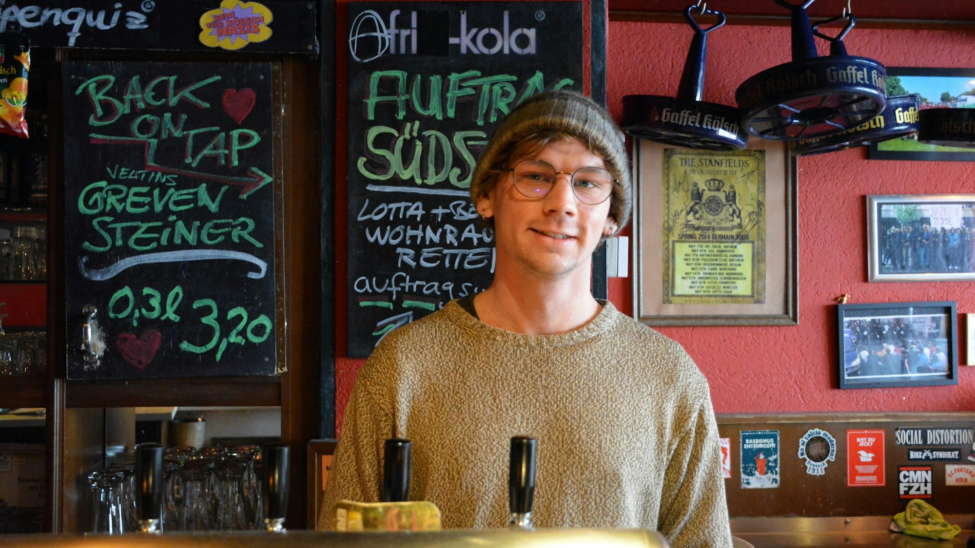 Ein junger Mann mit Mütze steht hinter einem Zapfhahn in der „Lotta“.