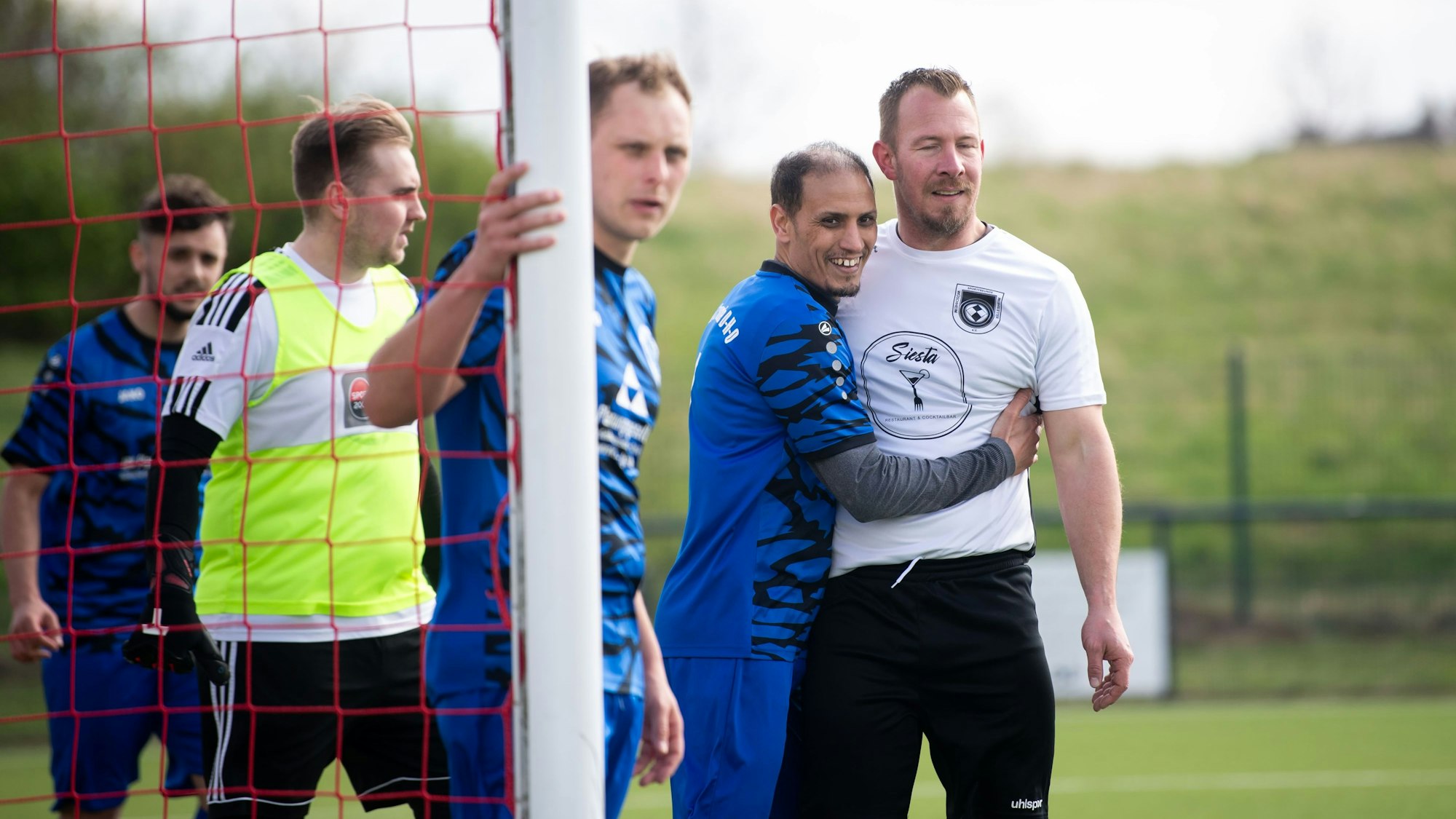 Das Bild zeigt eine Szene vor einem Eckball. Ein Spieler der Sportfreunde DHO nimmt seinen Gegenspieler freundschaftlich in den Arm.