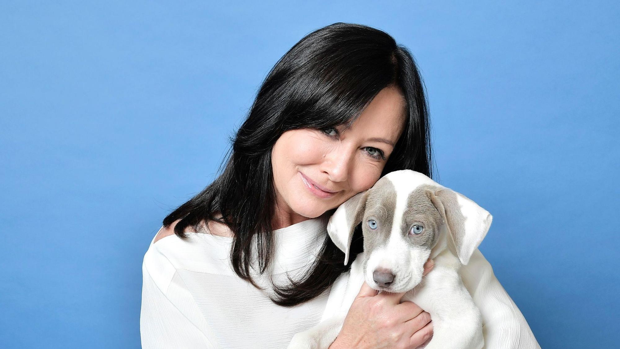 Shannen Doherty hält einen Hund im Arm.