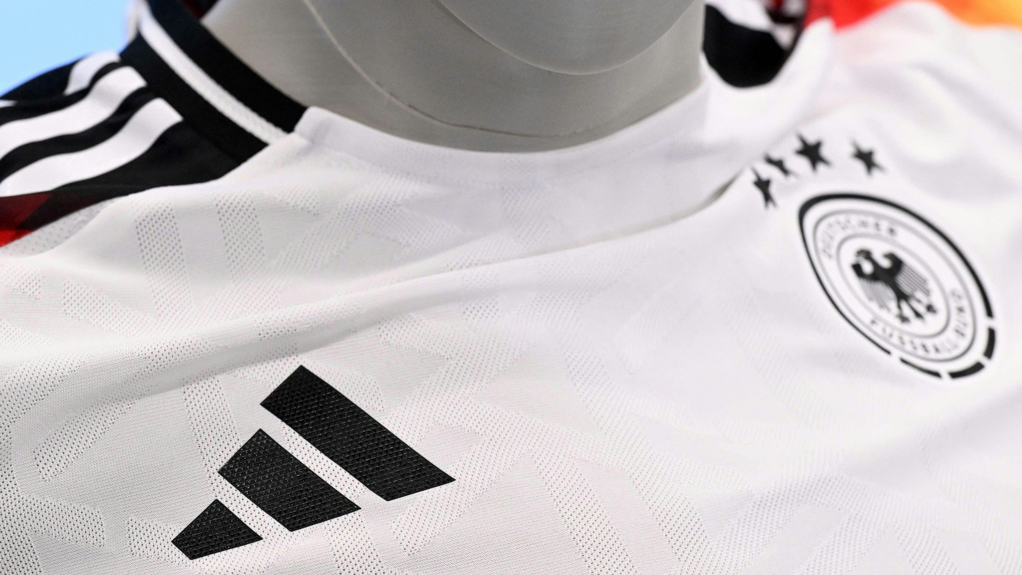 Das Oberteil des neuen Fußball-Nationaltrikots trägt die markenspezifischen drei Streifen des bisherigen DFB-Ausrüsters Adidas auf den Schultern sowie das aus drei Streifen bestehende Adidas-Dreieck unterhalb des rechten Schlüsselbeins.