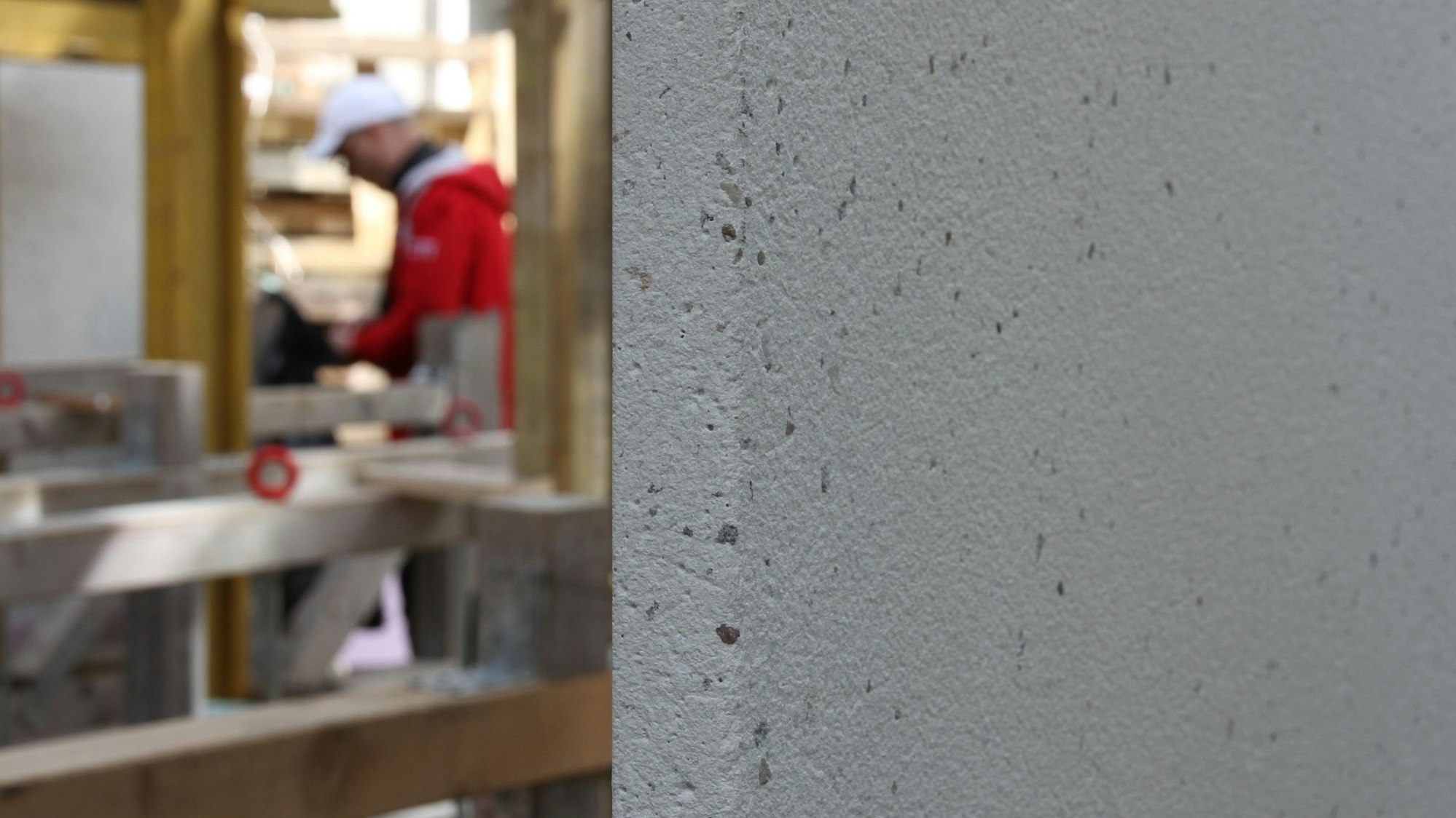 Eine helle Betonplatte, im Hintergrund ein Bauarbeiter