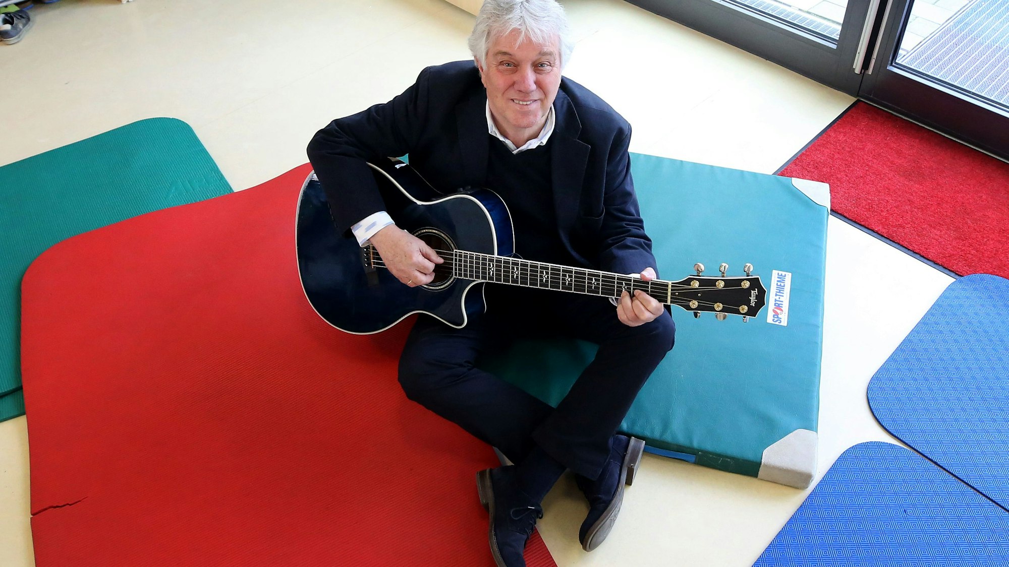 Kinderliedermacher Rolf Zuckowski sitzt in einer Kita während der Vorstellung eines Hörspiels.