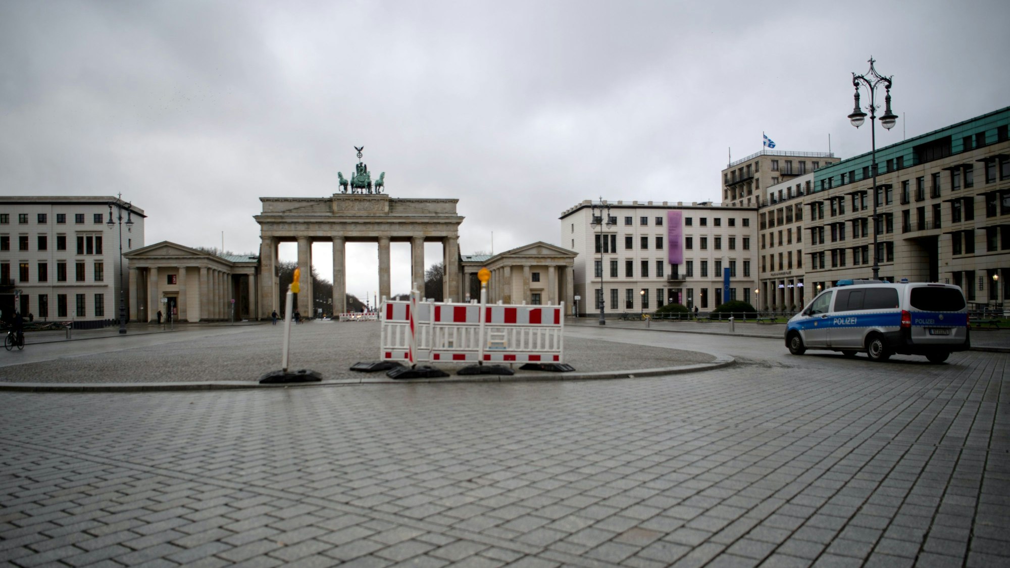 ARCHIV - 06.01.2021, Berlin: Ein Polizeifahrzeug fährt einen Tag nach dem Bund-Länder-Beschluss über eine Verlängerung des Lockdown über den fast menschenleeren Platz vor dem Brandenburger Tor.