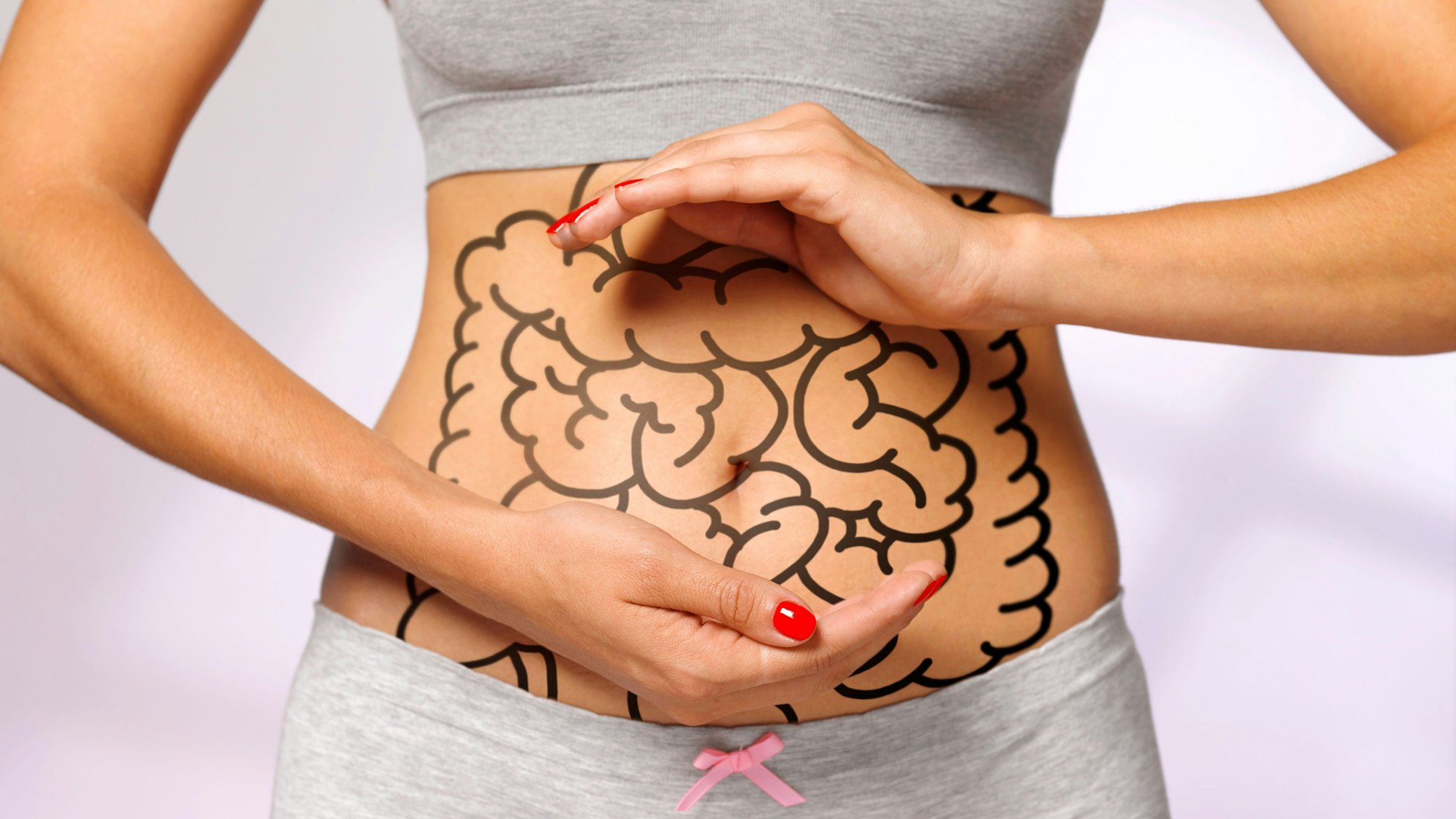Eine Frau hält schützend ihre Hände über einen eingezeichneten Darm Foto: Getty Images/The Image Bank RF