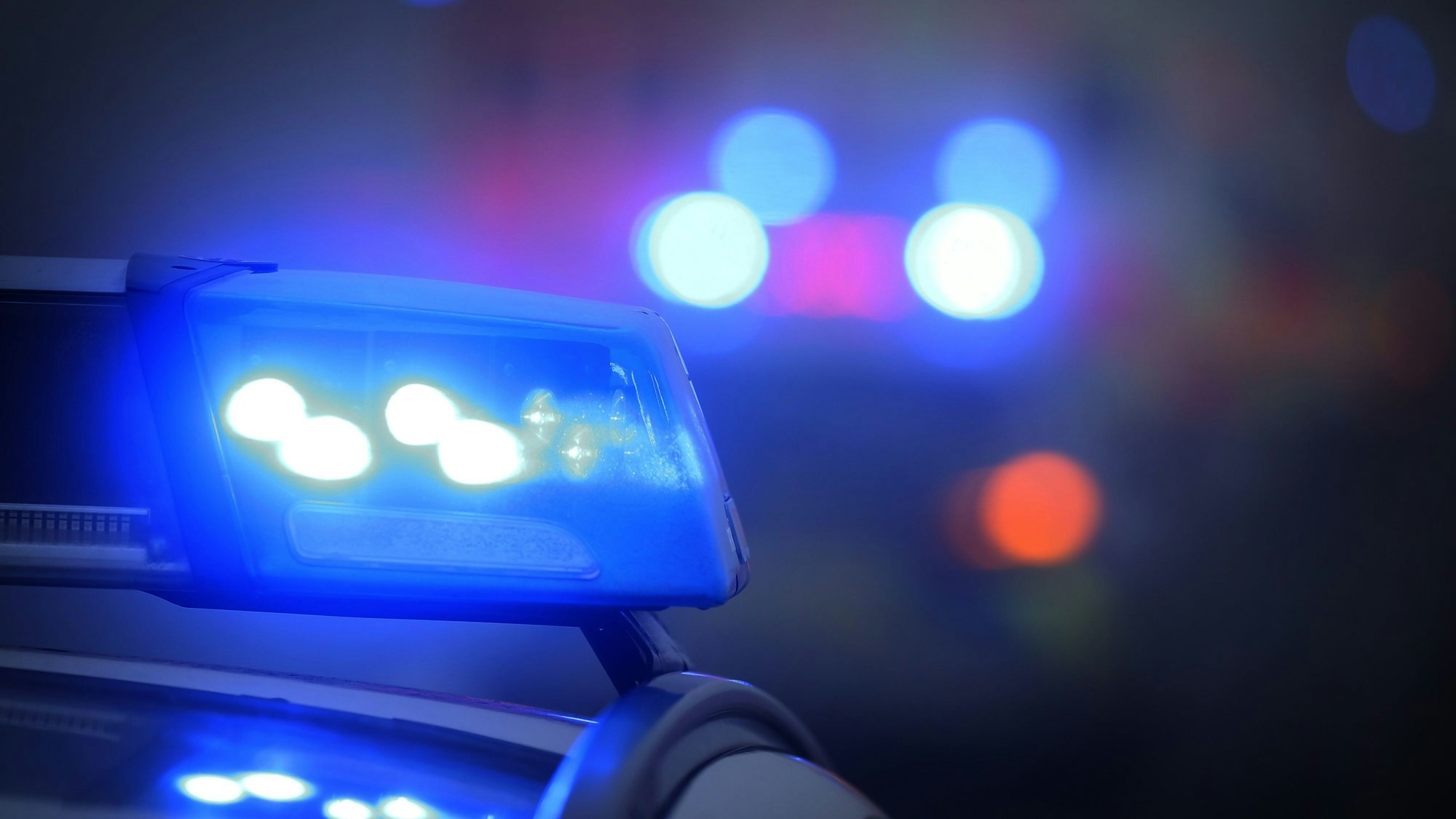 Ein Polizeiauto mit eingeschaltetem Blaulicht steht an einer Einsatzstelle.