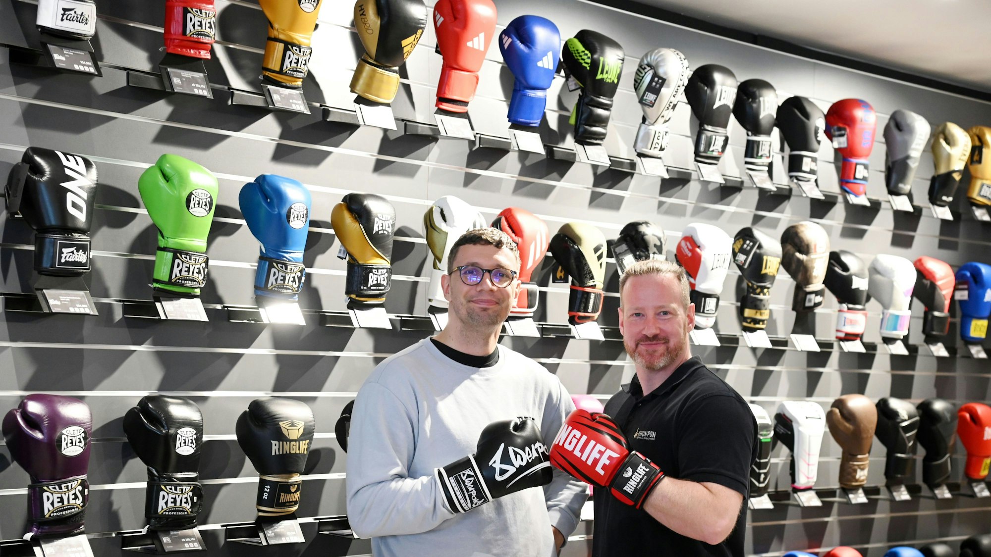 Mitinhaber Bruno Kabus (l.) und Geschäftsleiter Christoph Feldhaus vor der Wand mit 150 Boxhandschuh-Modellen