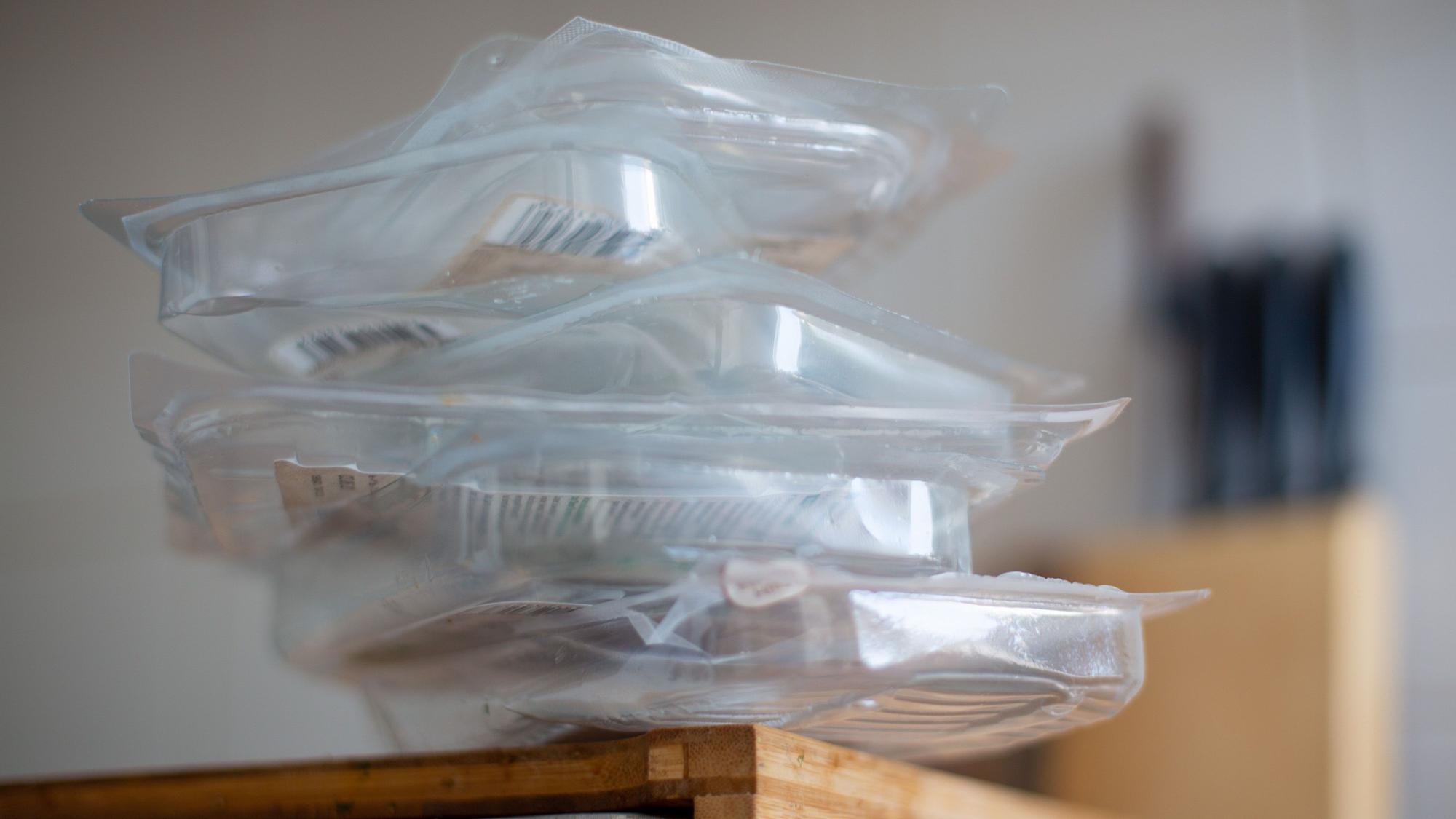 Gebrauchte Verpackungen für Wurst und Käse liegen auf einem Brett in einer Wohnungsküche gestapelt.