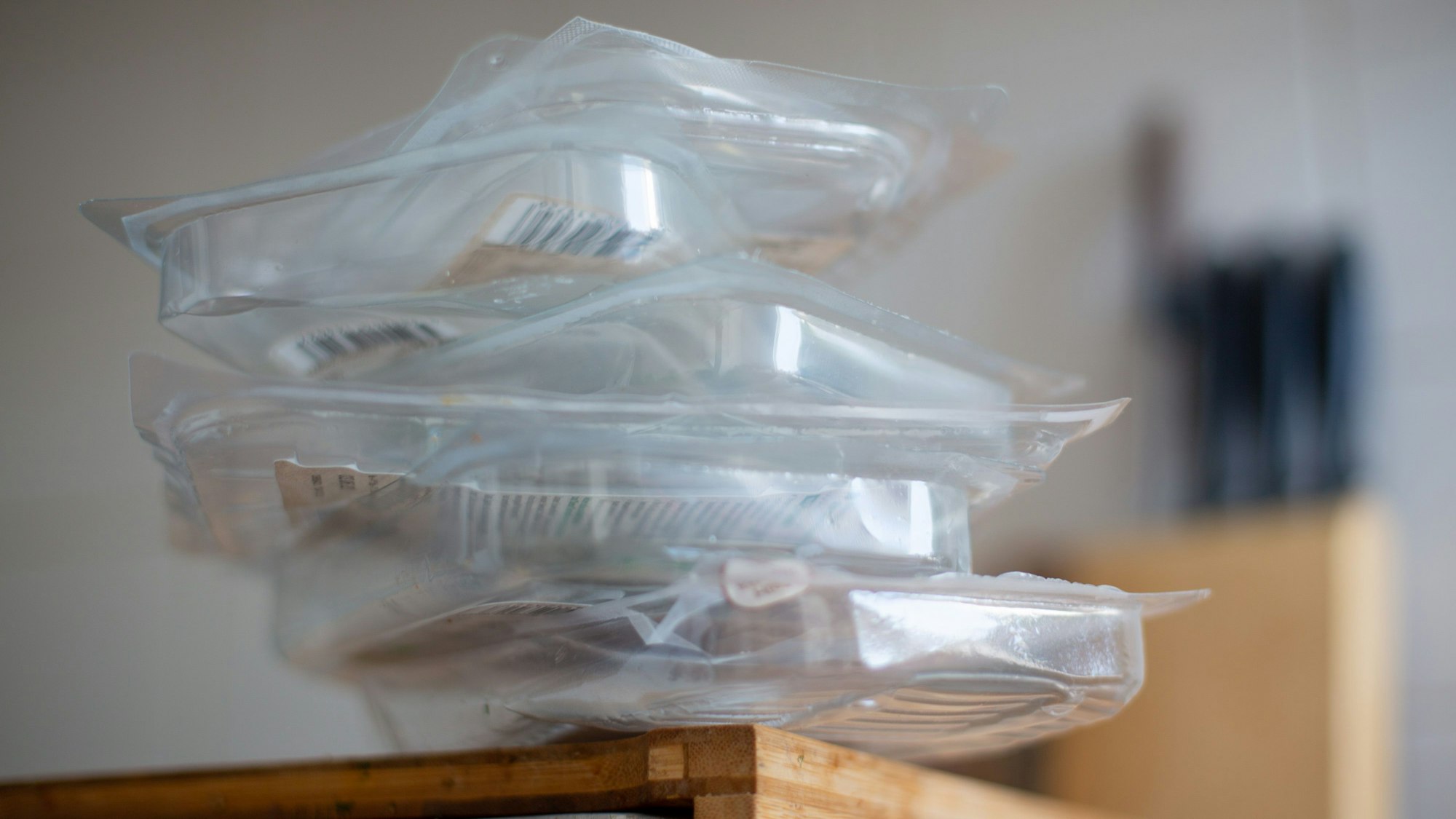 Gebrauchte Verpackungen für Wurst und Käse liegen auf einem Brett in einer Wohnungsküche gestapelt.