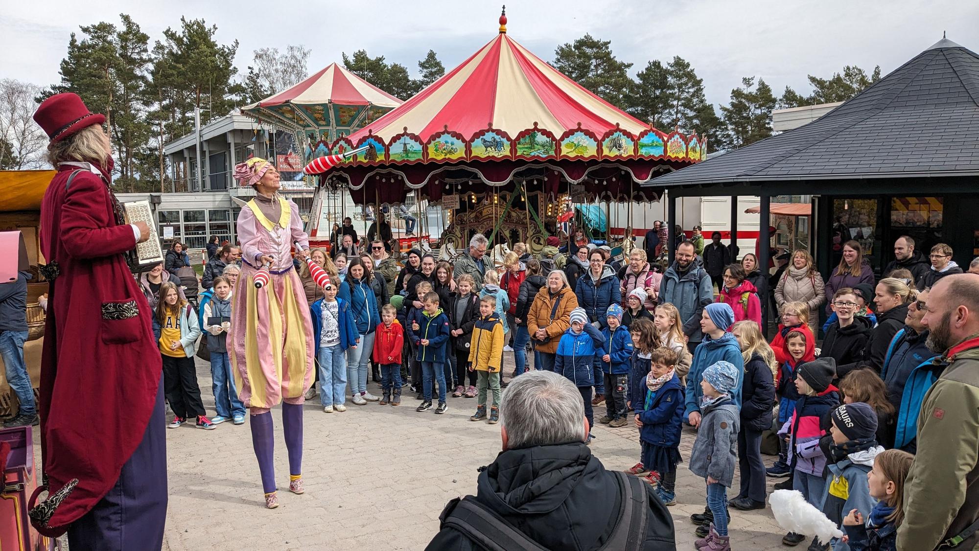 Zwei Stelzenläufer sind auf dem Jahrmarkt Anno dazumal im Kommerner Freilichtmuseum. Zahlreiche Zuschauer beobachten sie.