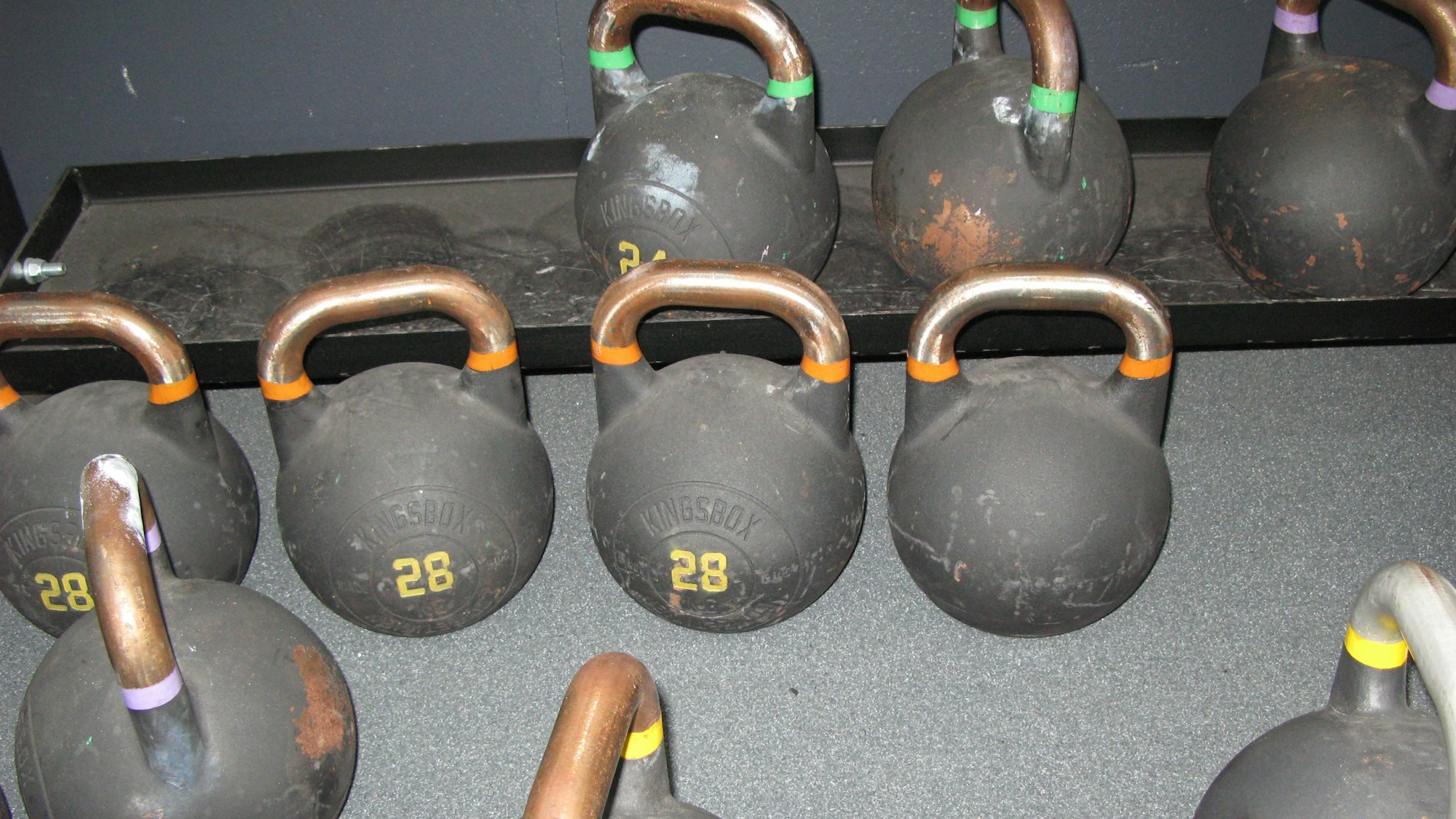 Das Bild zeigt zehn eiserne Gewichtskugeln mit Tragegriffen.