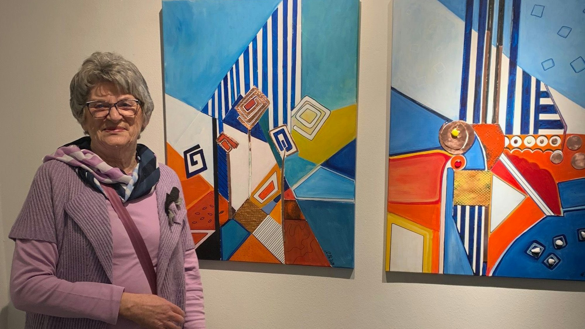 Eine Frau steht neben zwei farbigen Kunstwerken.