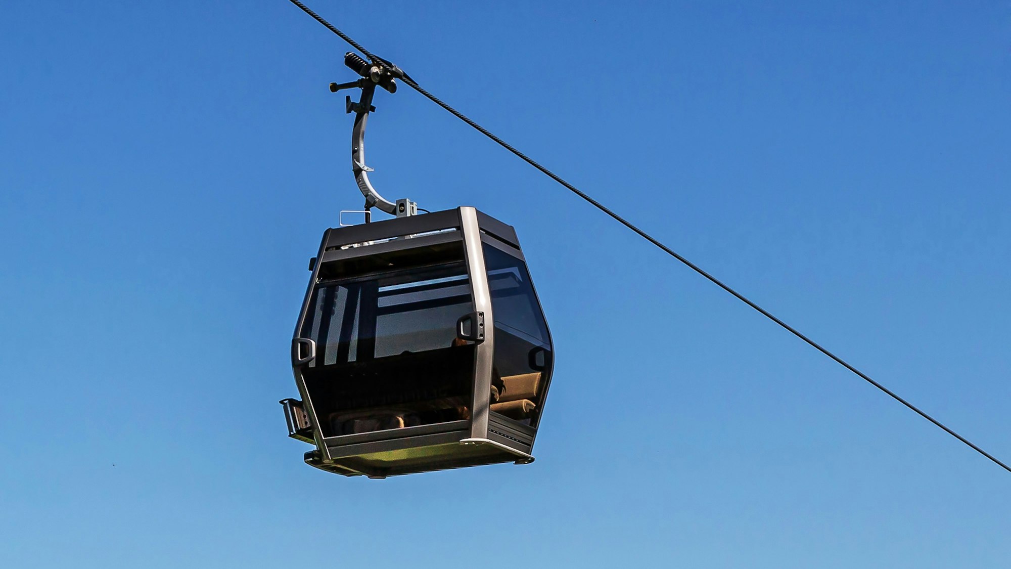 Die Kabine einer Seilbahn vor blauem Himmel.