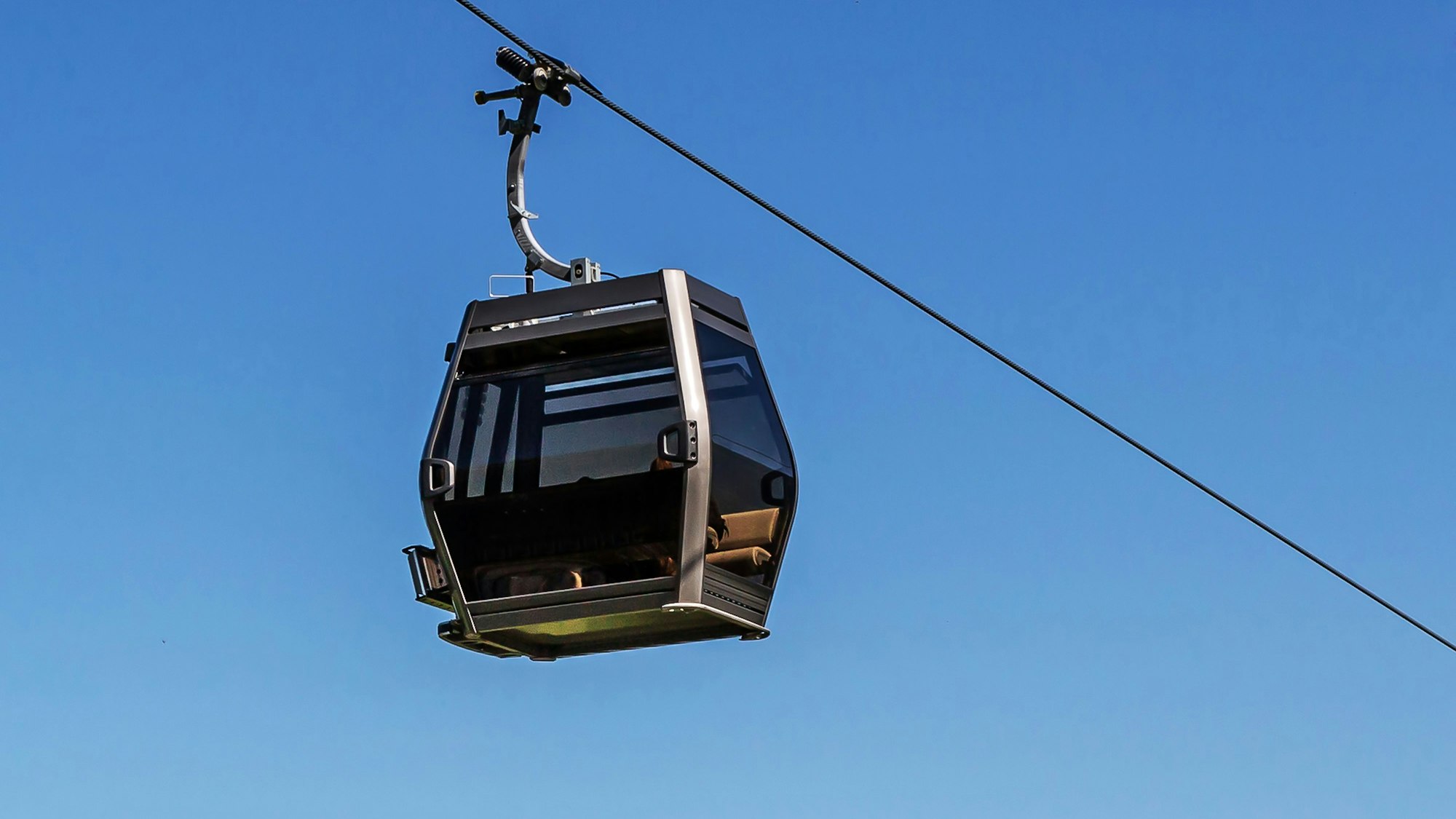 Die Kabine einer Seilbahn vor blauem Himmel.