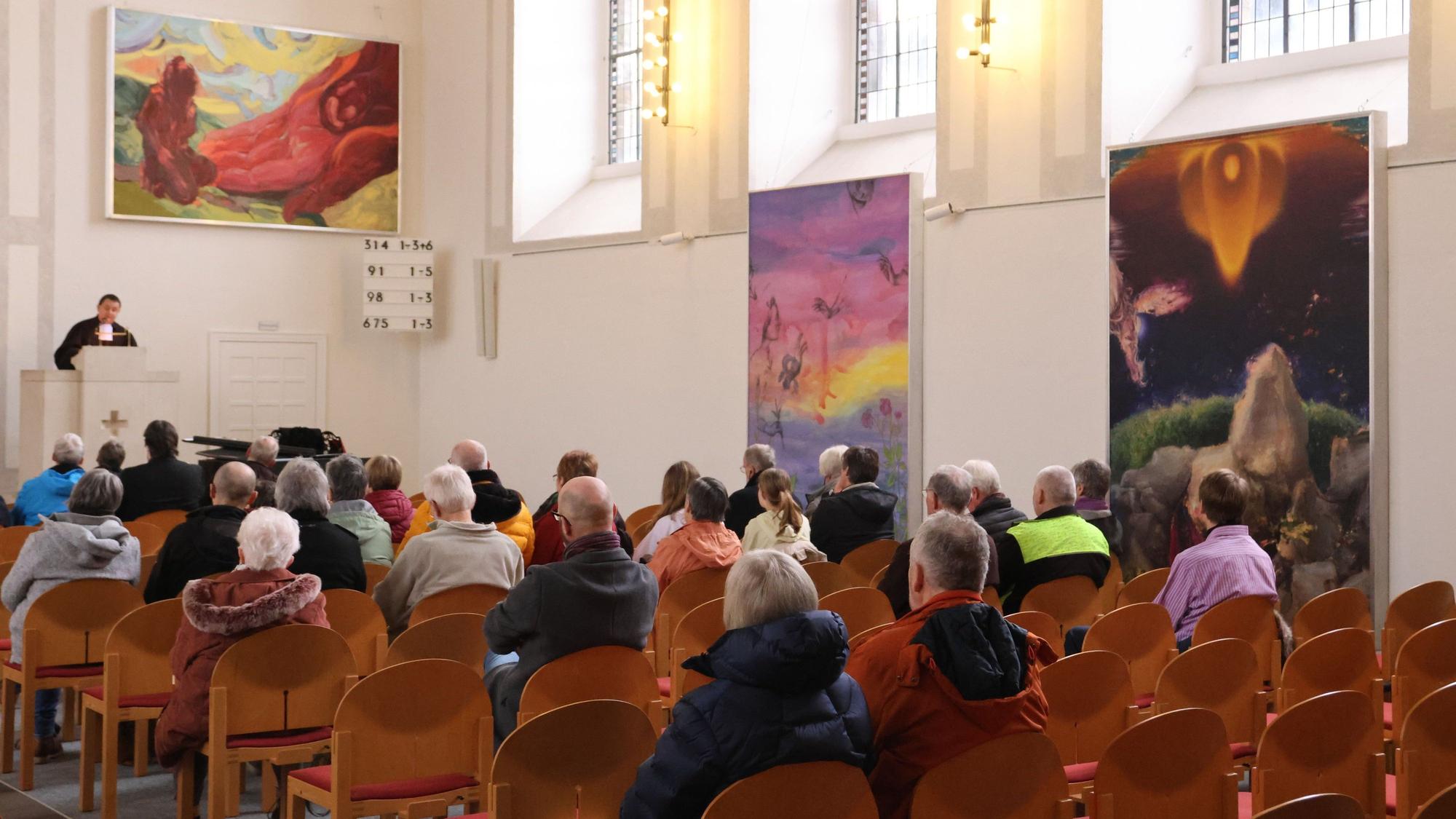 Eine gut besuchte Kirche. Ein Pfarrer steht an der Kanzel und spricht zu den Besuchern.