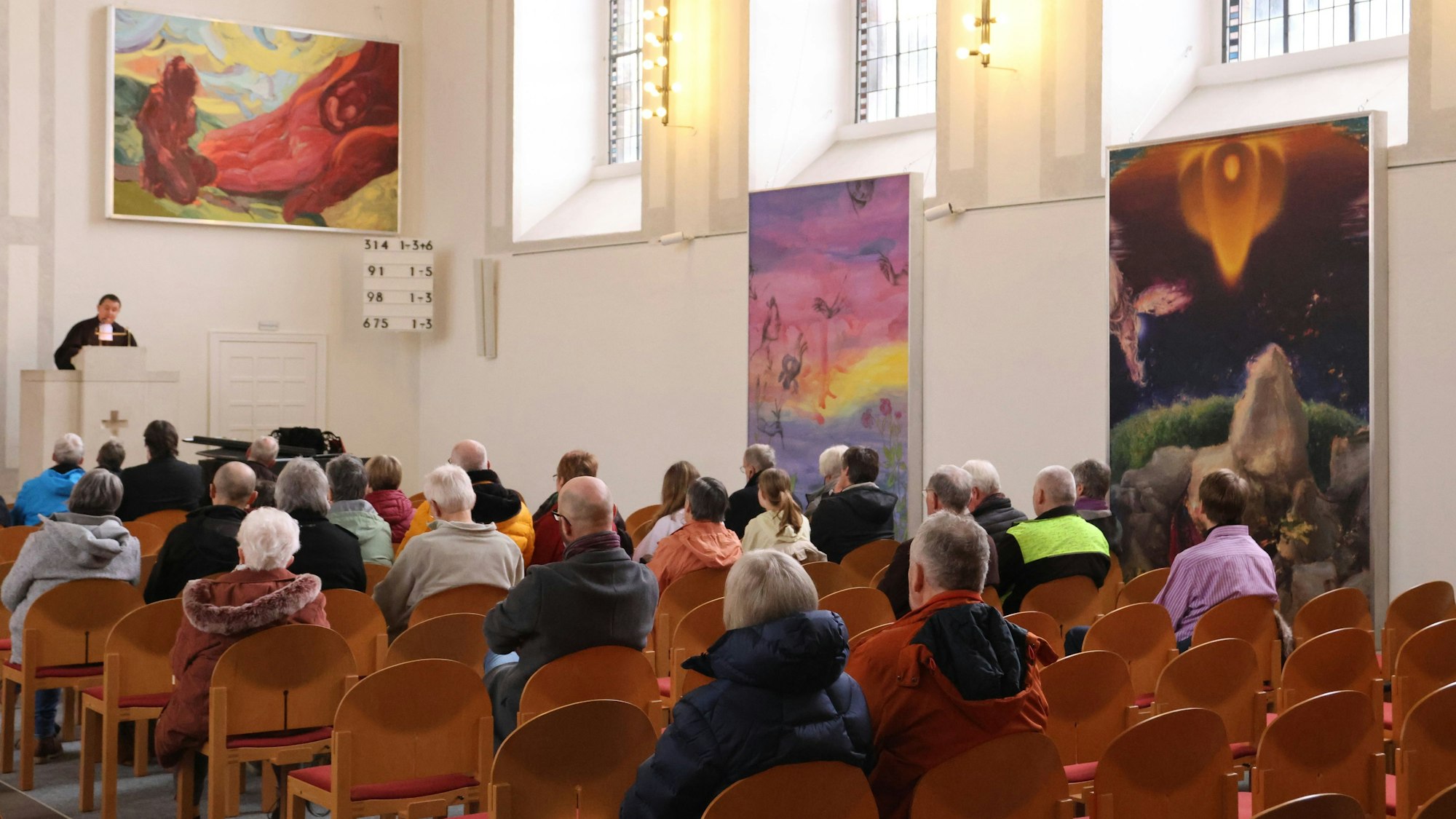 Eine gut besuchte Kirche. Ein Pfarrer steht an der Kanzel und spricht zu den Besuchern.