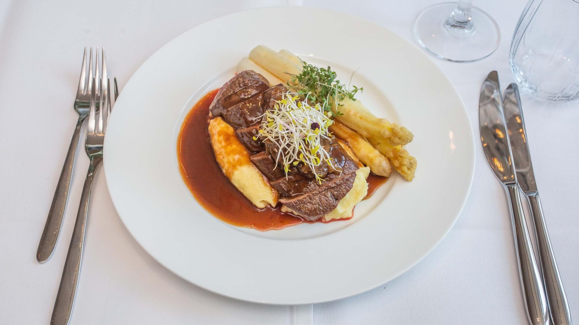 Der Hauptgang angerichtet: Lammlachs mit Kartoffelstampf, weißem Spargel, Zwiebelmarmelade und Lamm Jus.
