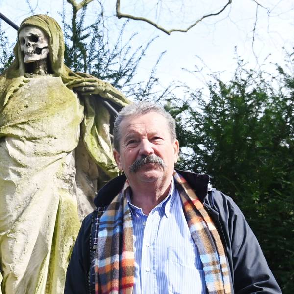 Porträt von Friedhofsleiter vor einer Skulptur des Sensenmannes.