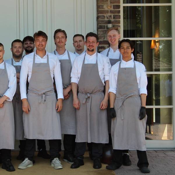 Zu sehen sind der Küchenchef und sein Team vor dem Eingang ins Restaurant.