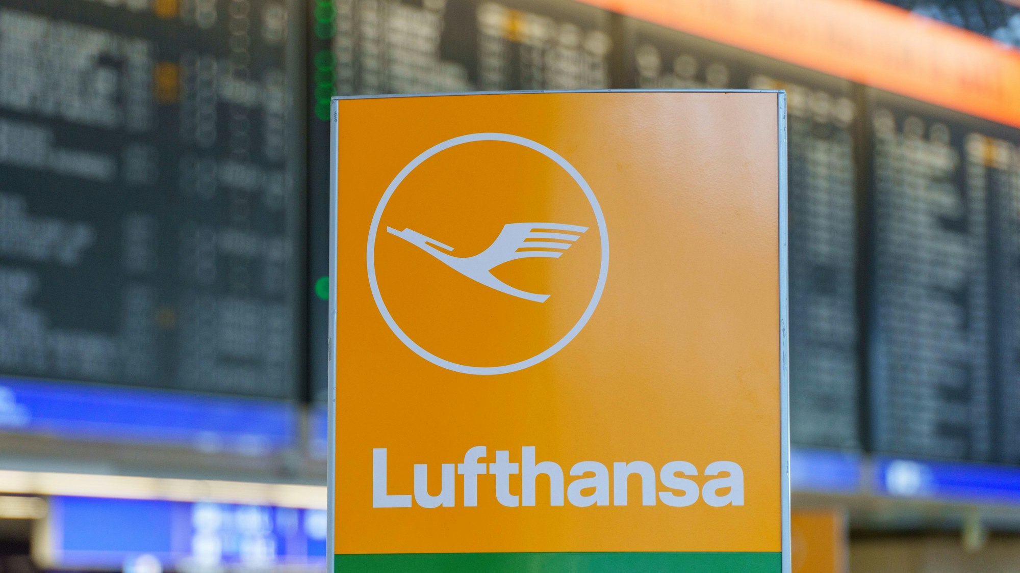 ARCHIV - 06.03.2024, Hessen, Frankfurt/Main: Das Logo der Fluggesellschaft Lufthansa steht vor der Anzeigetafel in der Abflughalle im Terminal 1.