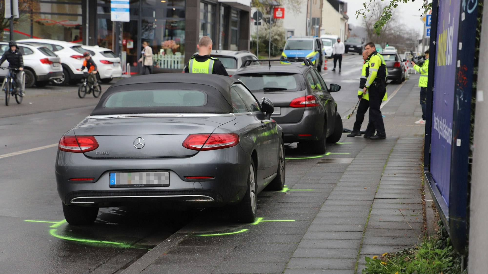 Autos stehen auf einem Bürgersteig. Polizisten haben Markierungen gezogen.