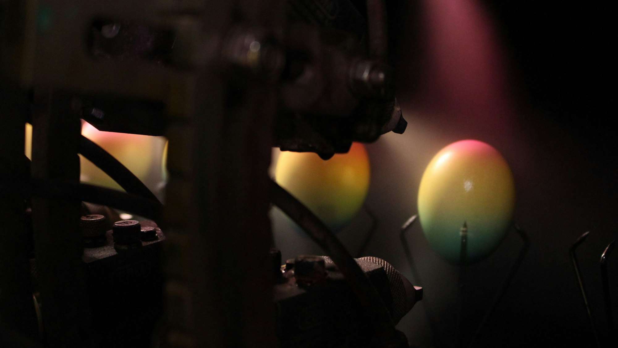 Ein Ei, das über ein Förderband bewegt wird, wird so mit Farbe besprüht, dass es am Ende als Regenbogen-Ei verpackt werden kann.