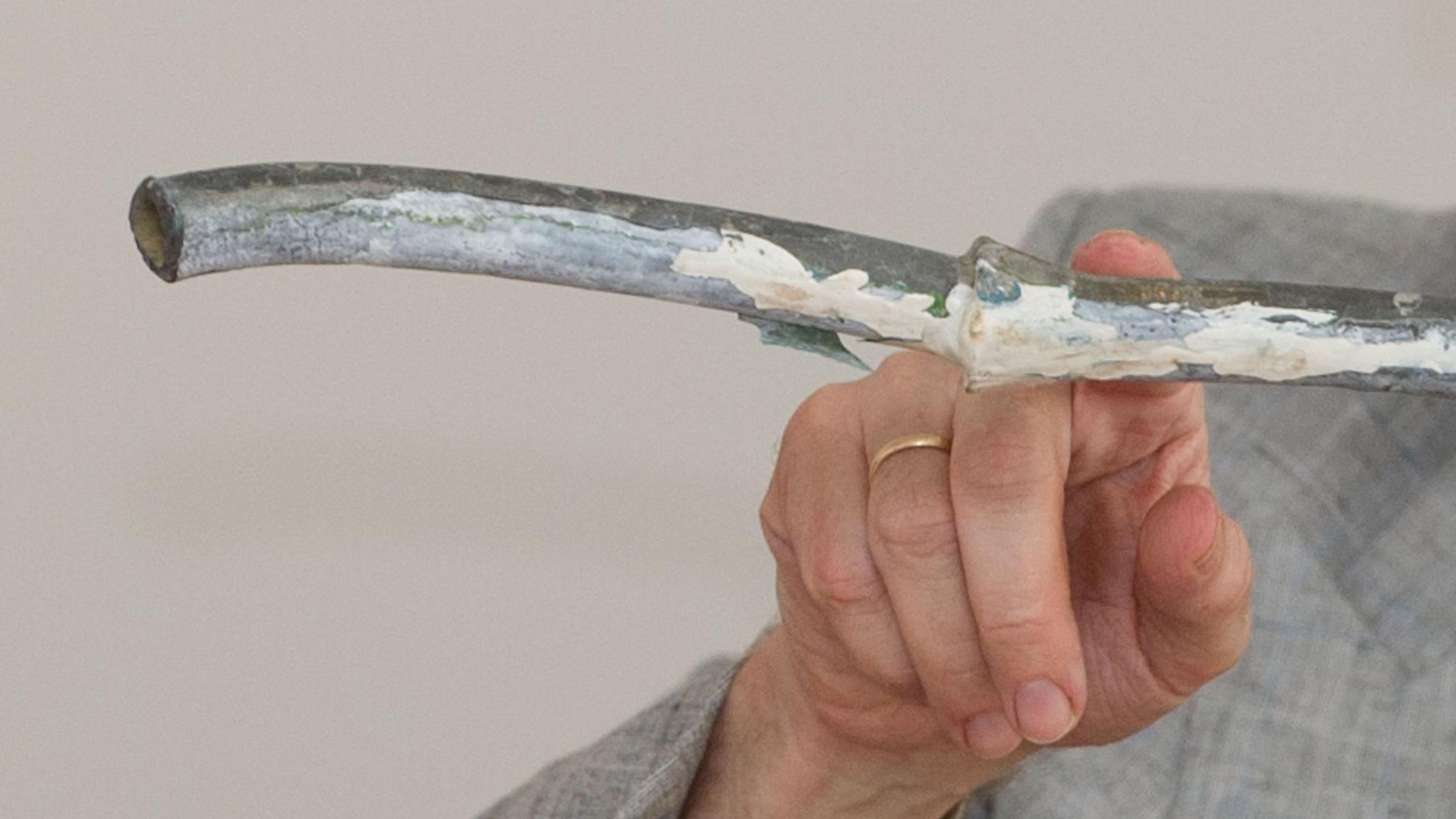 Ein Mann zeigt mit einem Finger auf ein Wasserrohr.