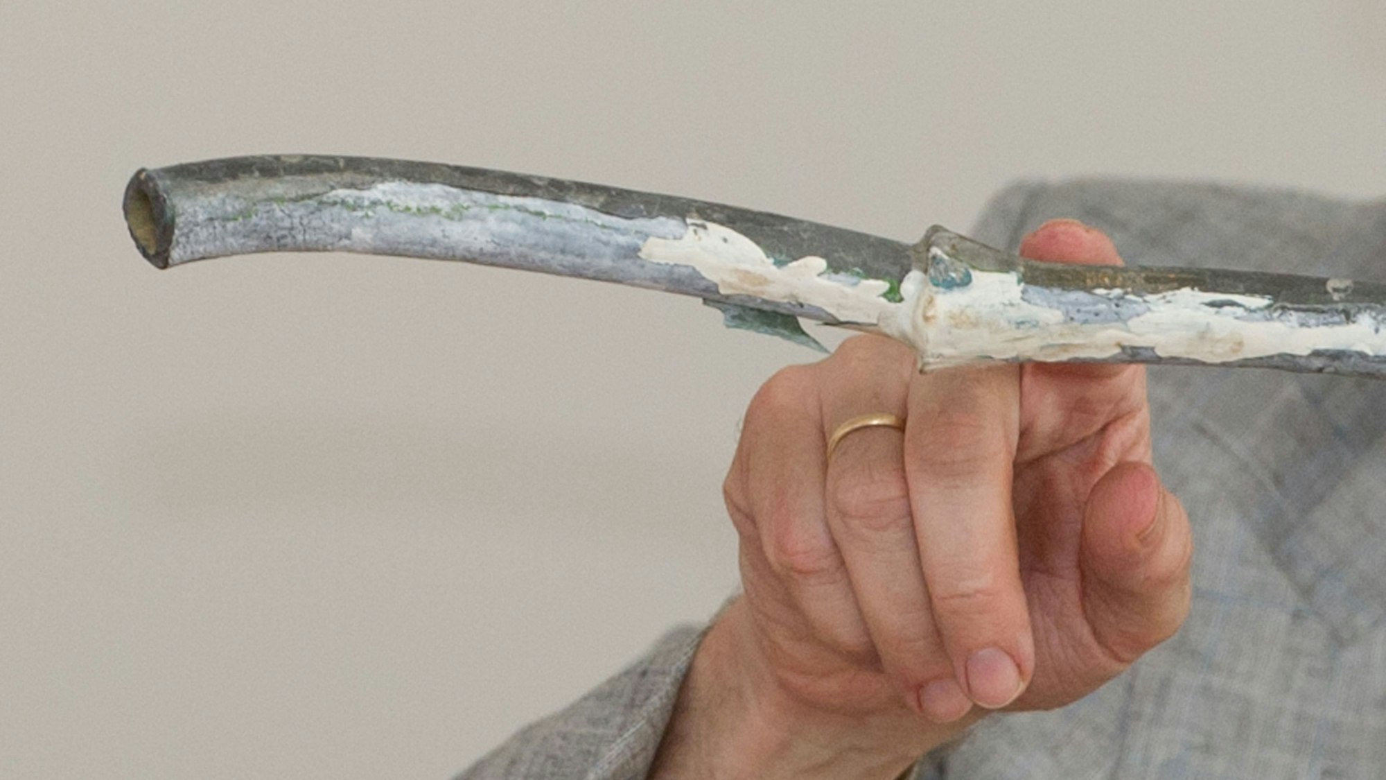 Ein Mann zeigt mit einem Finger auf ein Wasserrohr.