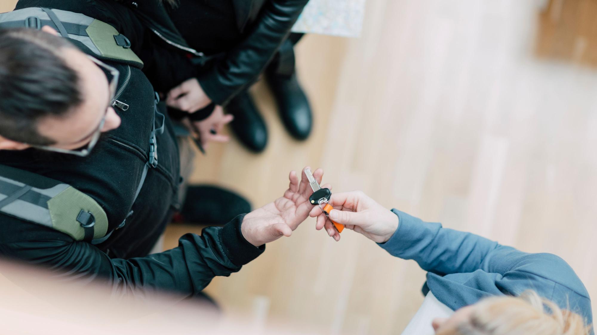 Eine Person übergibt zwei anderen Personen einen Schlüssel