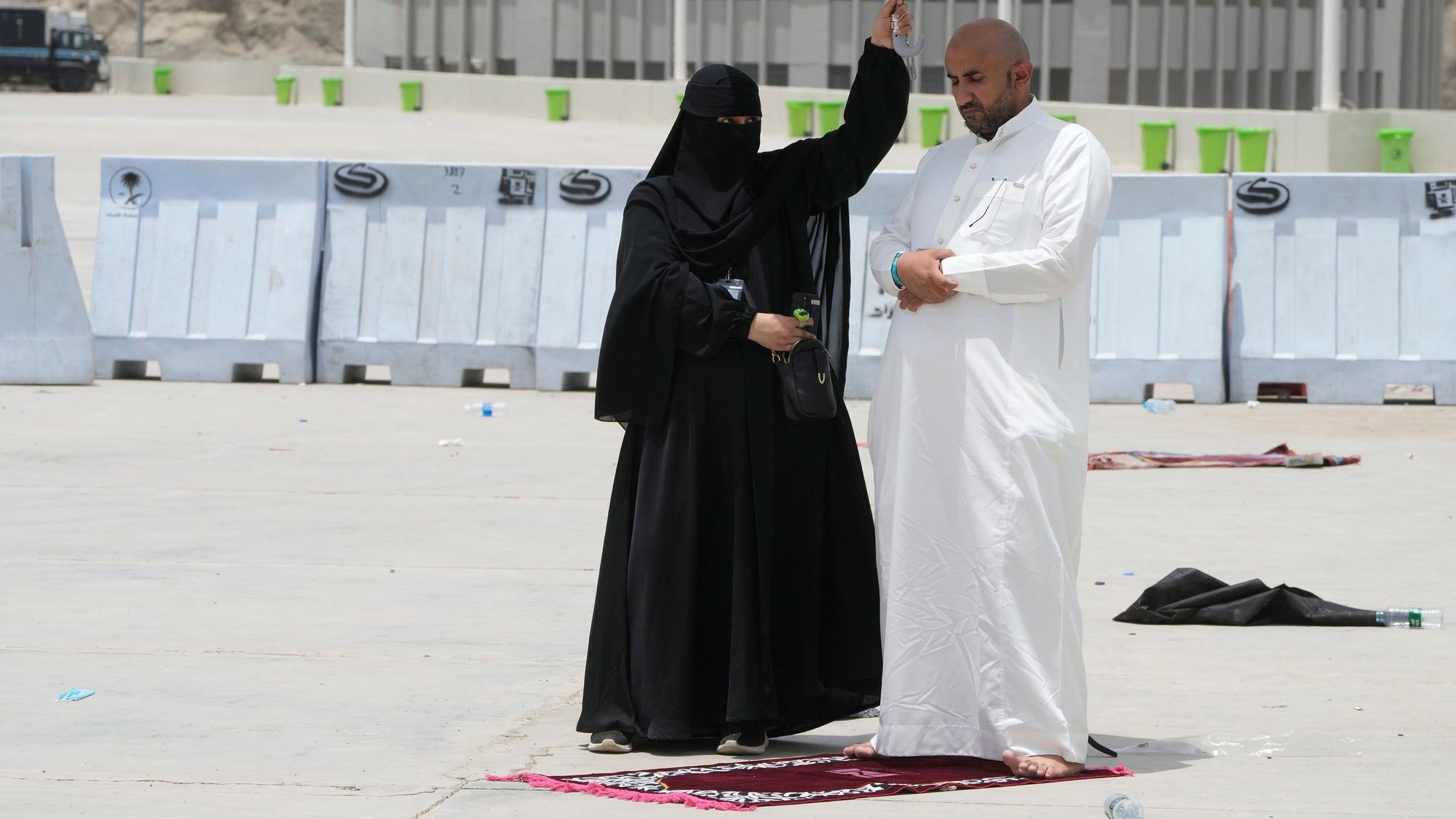 Eine Frau hält einen Schirm über einen Mann der sein Gebet am letzten Tag der Hadsch in Mekka in Saudi-Arabien verrichtet.