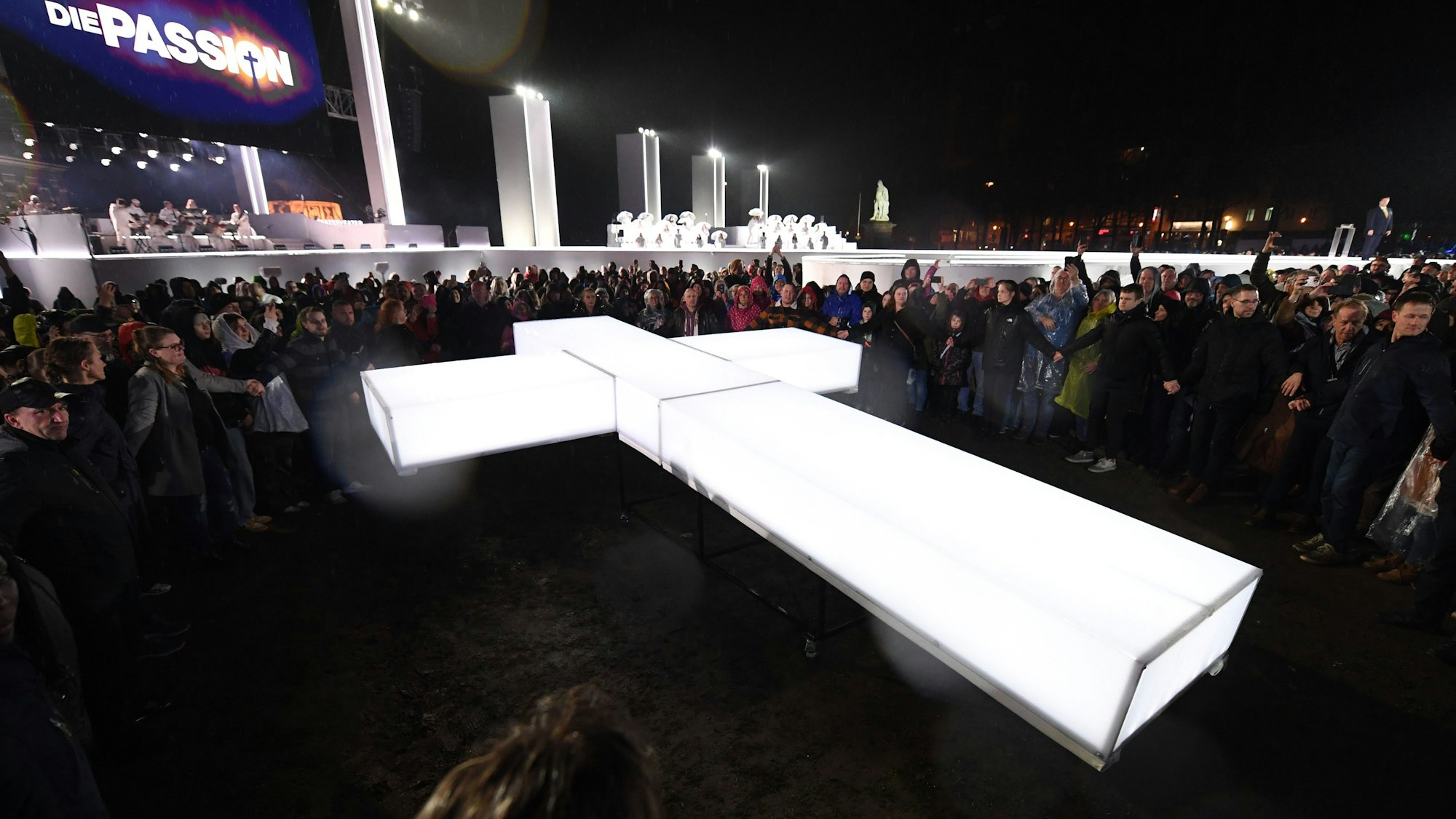 27.03.2024, Hessen, Kassel: Ein leuchtendes Kreuz wird bei der RTL-Oster-Produktion «Die Passion» auf den Friedrichsplatz getragen. RTL inszeniert zum zweiten Mal live das Musik-Spektakel «Die Passion - Die größte Geschichte aller Zeiten». Foto: Swen Pförtner/dpa +++ dpa-Bildfunk +++