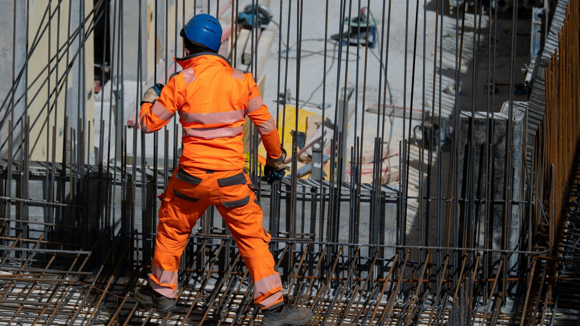 Ein Bauarbeiter verlegt auf einer Baustelle Stahlmatten.