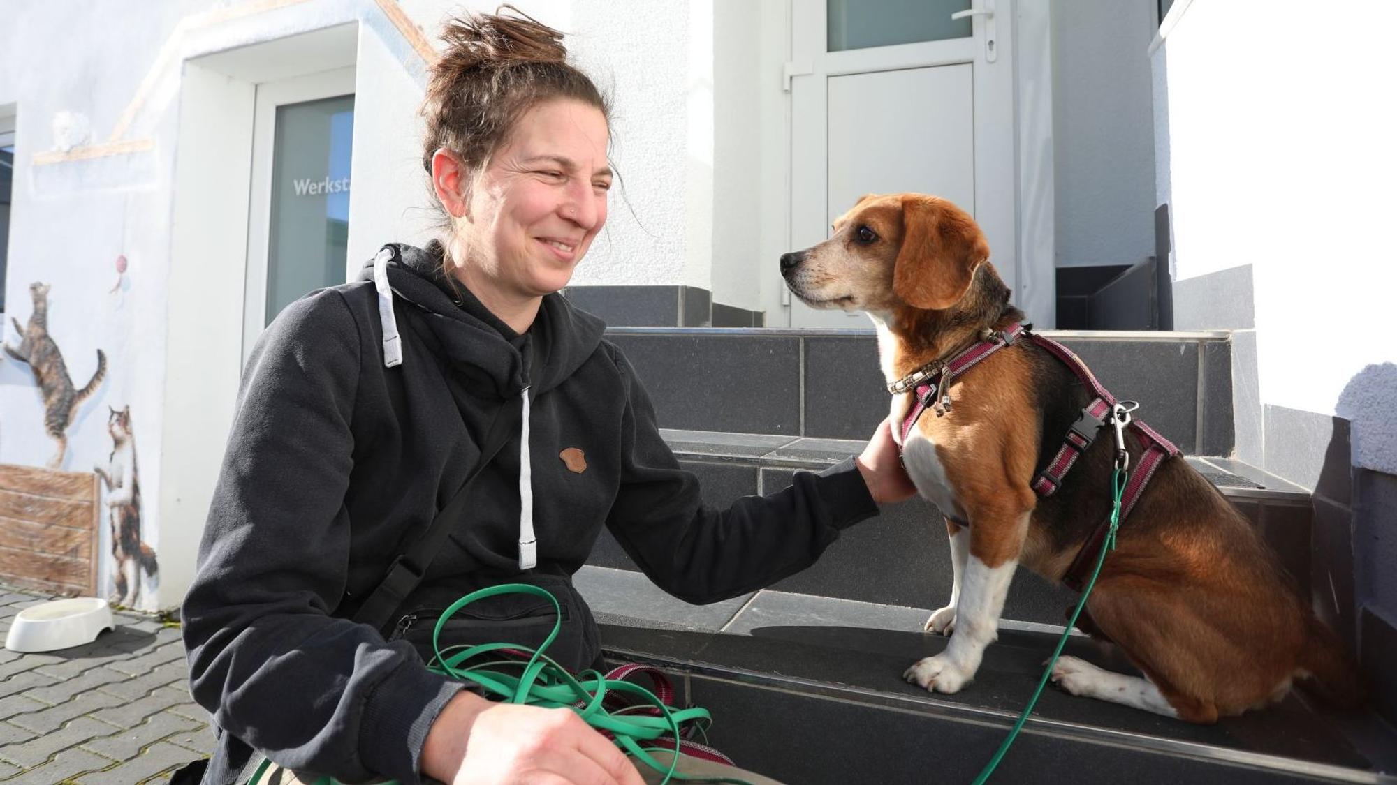 Eine Frau und ein Hund sitzen nebeneinander auf einer Treppenstufe.