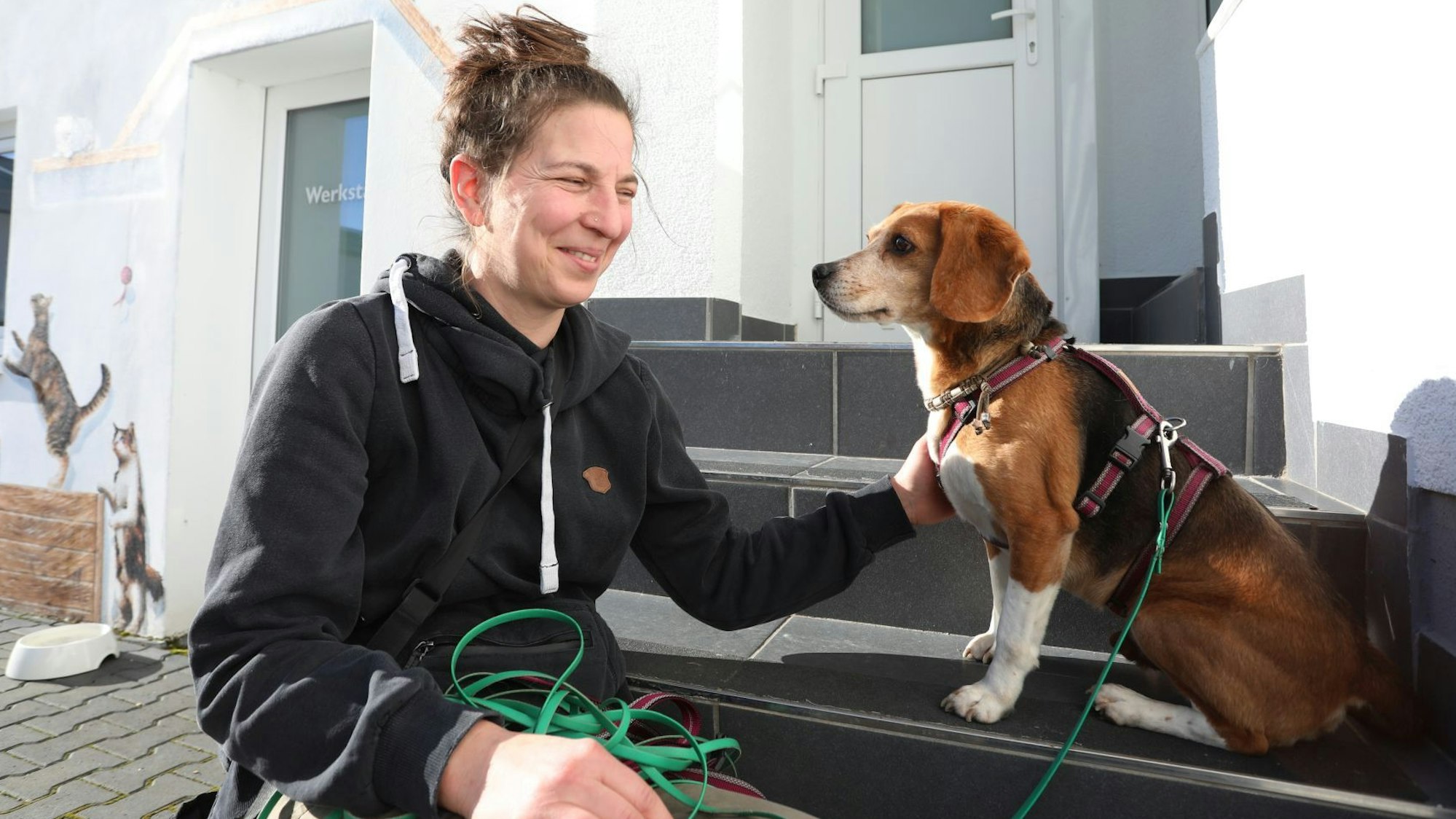 Eine Frau und ein Hund sitzen nebeneinander auf einer Treppenstufe.