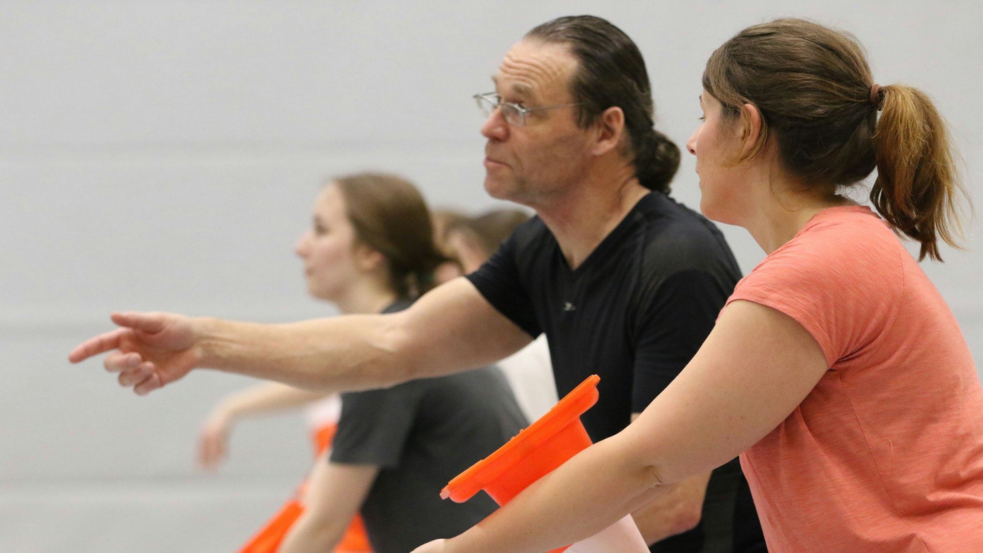 Trainer Andreas Bey steht in der Mitte und erklärt einer Volleyballerin etwas.