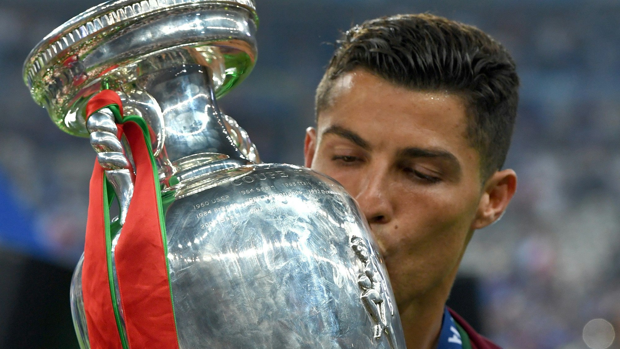 Auf dem Foto ist der portugiesische Nationalspieler Christiano Ronaldo zu sehen. Er küsst den EM-Pokal.
