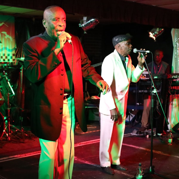 Zwei MEnschen stehen an Mikros und singen