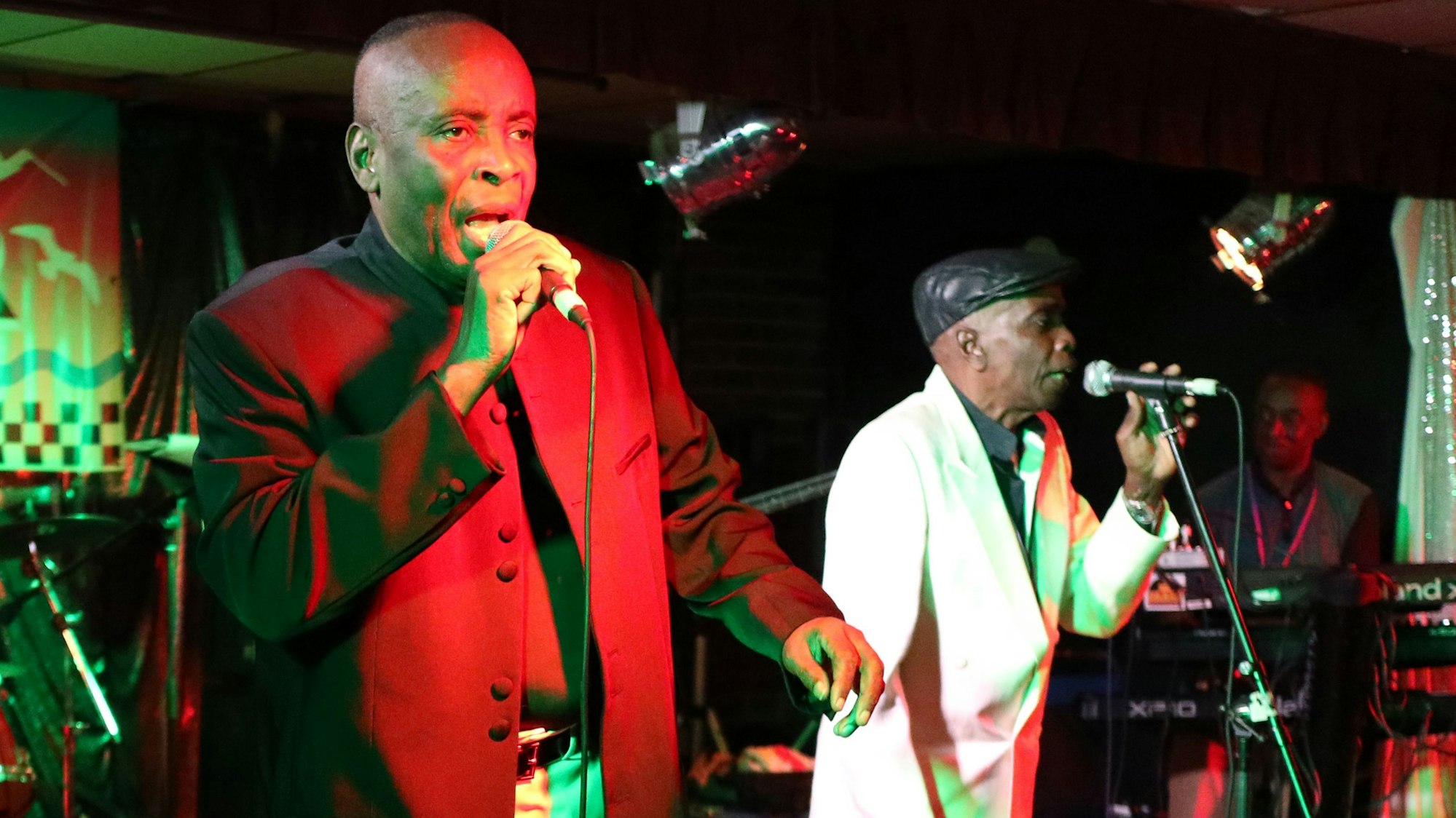 Zwei MEnschen stehen an Mikros und singen