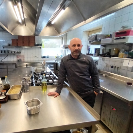 Mann in Kochjacke in einer Restaurantküche