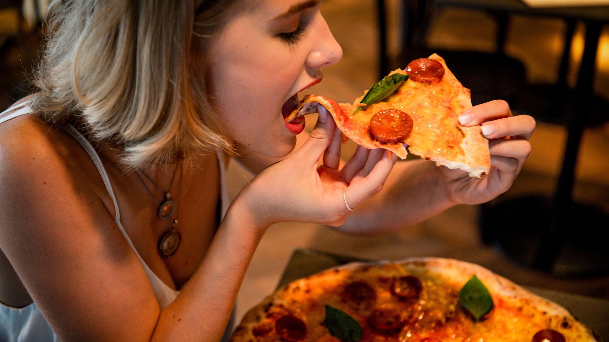 Zu sehen ist eine Frau, die Pizza isst.