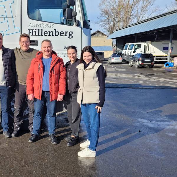 Eine Gruppe von Menschen steht untergehakt vor einem Lastzug im ukrainischen Butscha.