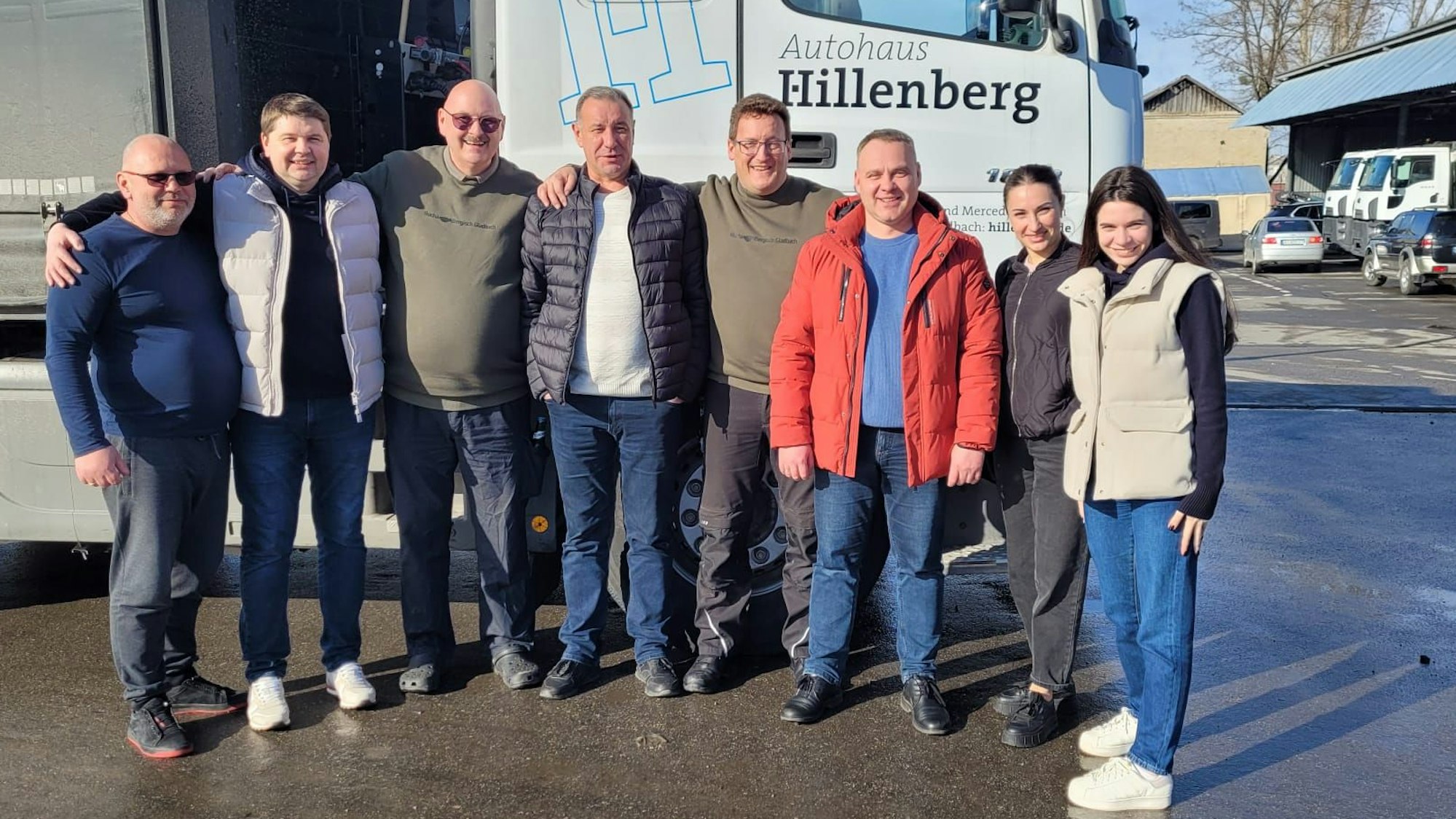 Eine Gruppe von Menschen steht untergehakt vor einem Lastzug im ukrainischen Butscha.