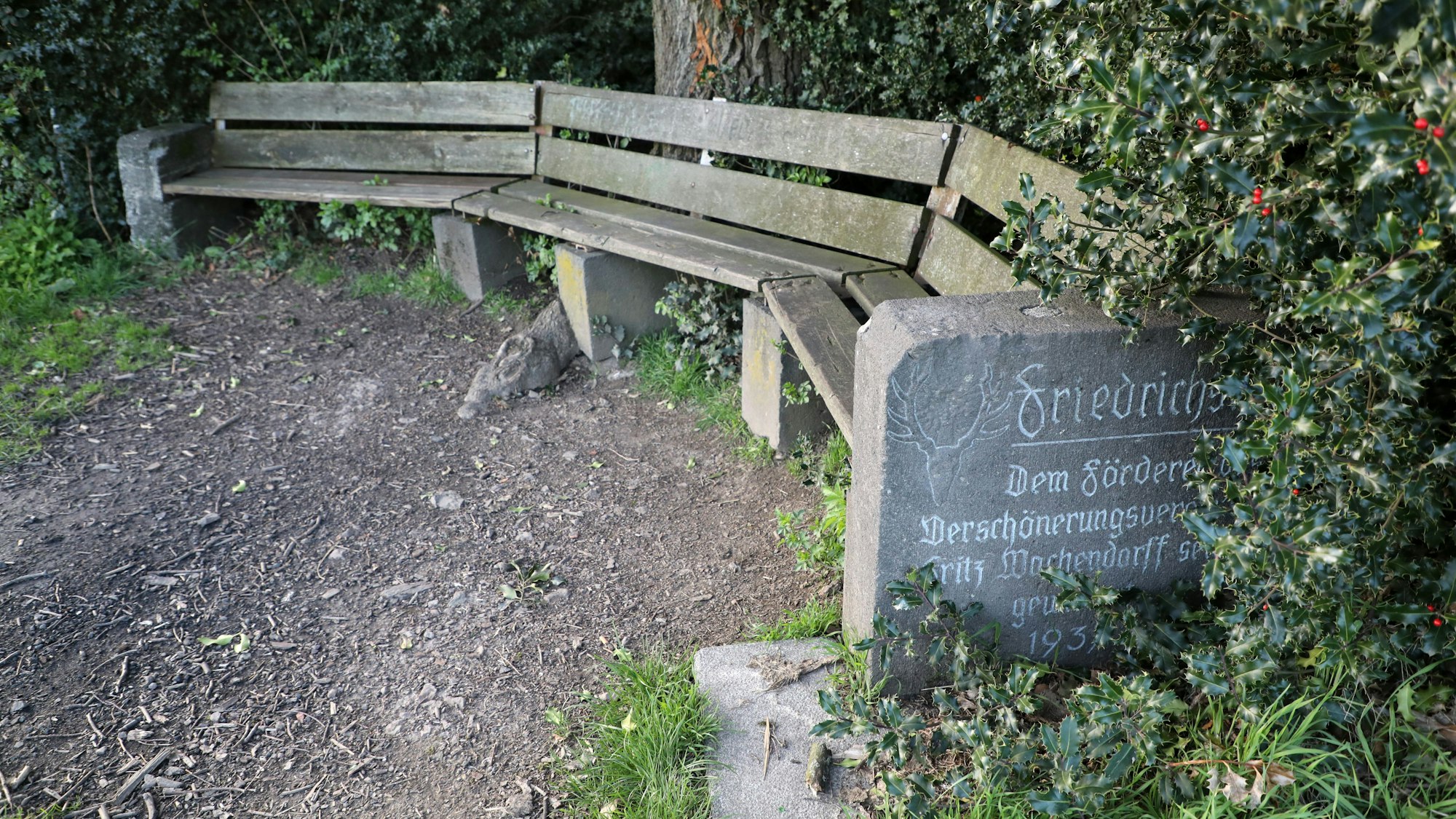 Eine geschwungener Sitzbank wird von Grabsteinen gefasst.