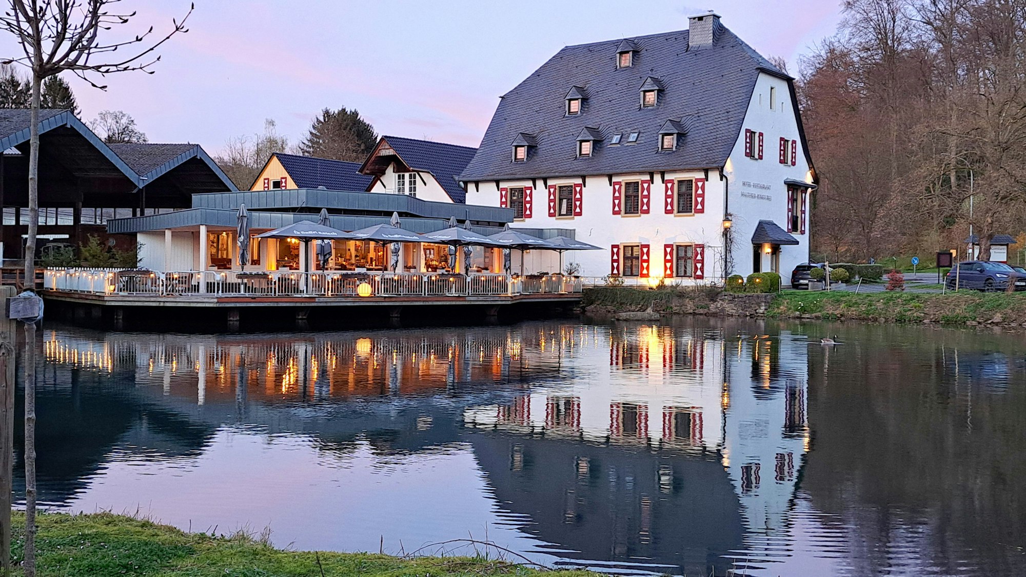 Hinter einem ehemaligen Mühlenteich steht ein historisches Gebäude.