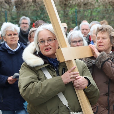 Das Bild zeigt mehrere Christen, die ein Holzkreuz tragen.