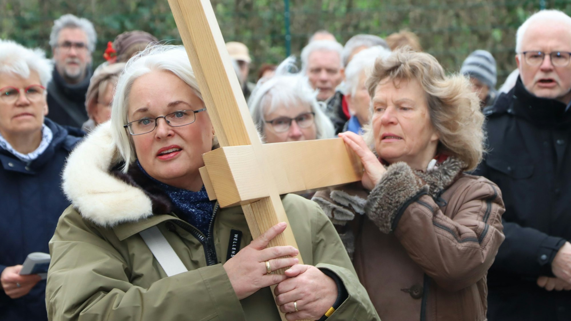 Das Bild zeigt mehrere Christen, die ein Holzkreuz tragen.