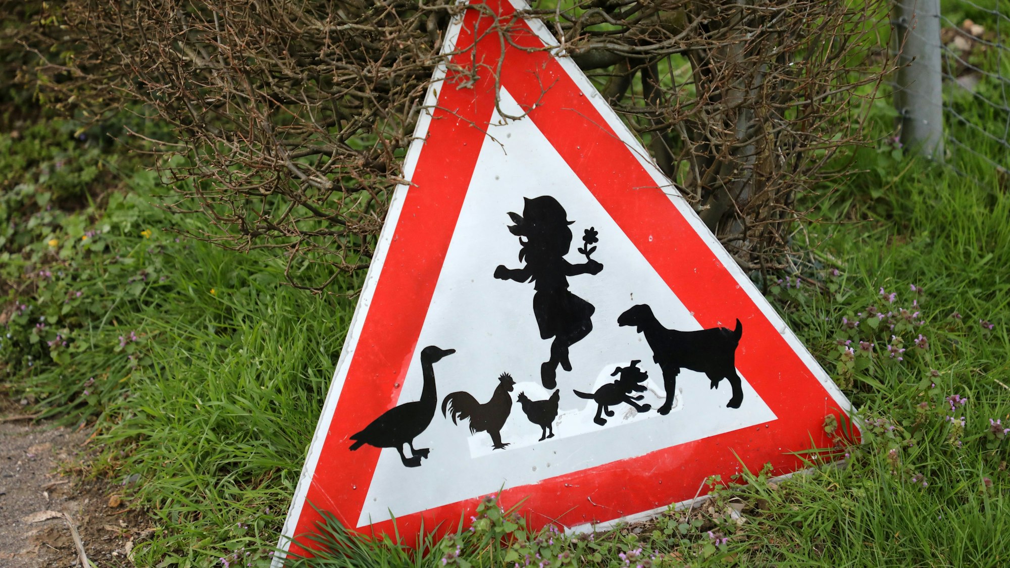 Auf einem Verkehrsschild sind ein Kind und Tiere zu sehen.