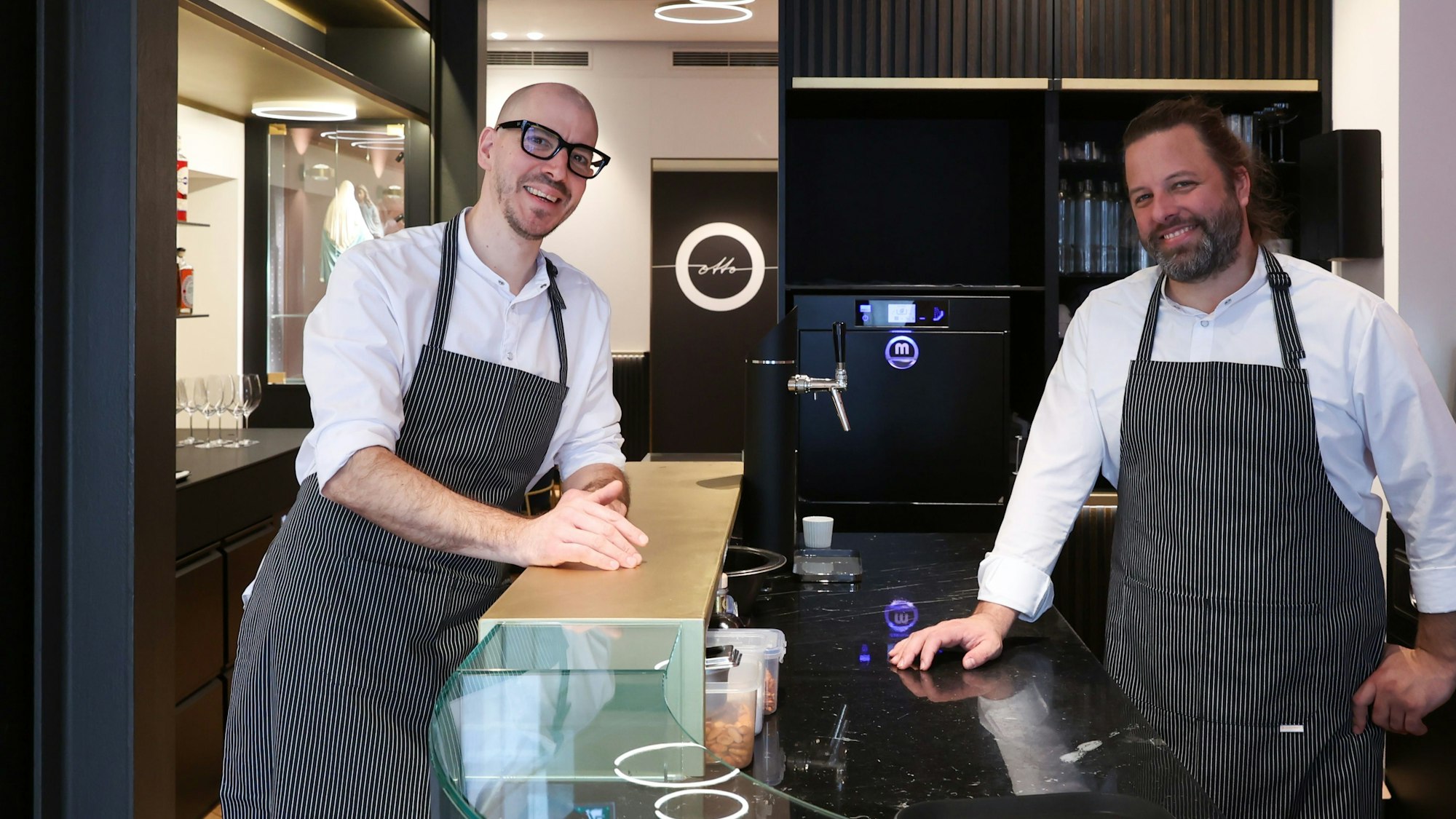 Zwei Männer stehen im Kölner Restaurant Ottio an einer Theke.